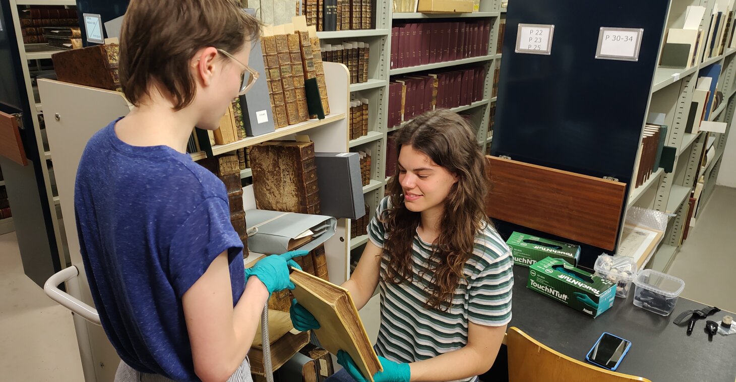 Jobstudenten Fiep en Annelien helpen bij het droogreinigen van boeken